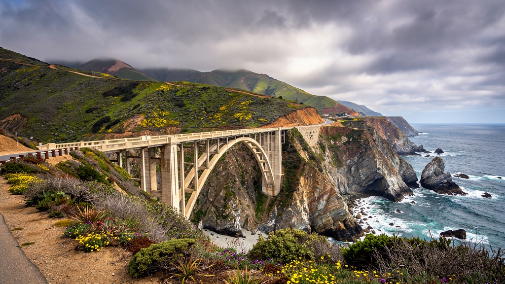 Bixby Creek Bridge Big Sur iconic arch bridge spanning a deep coastal canyon, green wildflower-covered mountains and Pacific below